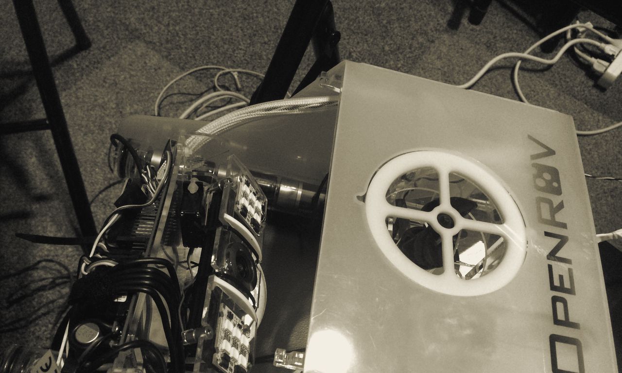 An OpenROV underwater drone with its electronics exposed on a workbench, a yellow tether attached.