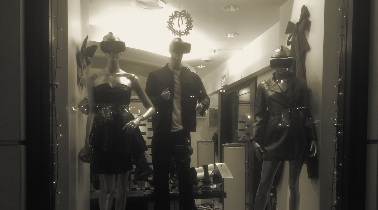 A shop window at night: three mannequins wearing VR headsets.